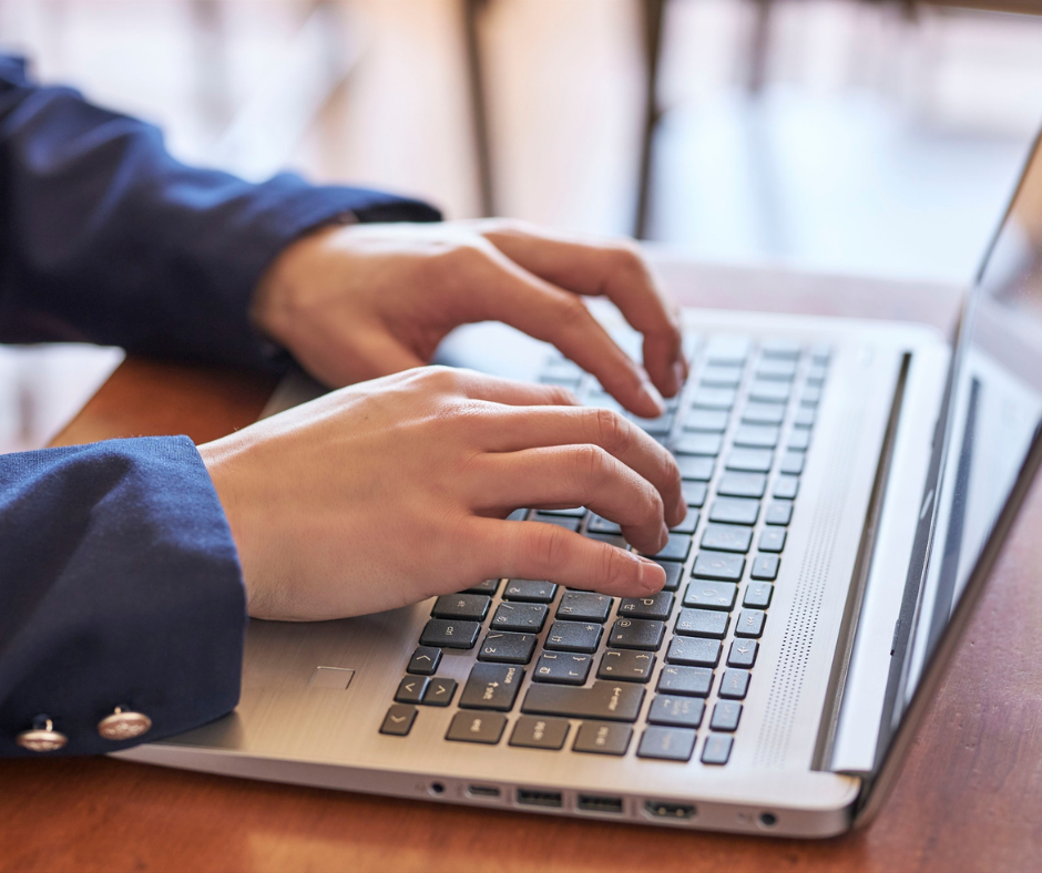 Professional using a keyboard to navigate a website on a desktop computer, with the screen content naturally blurred and unreadable